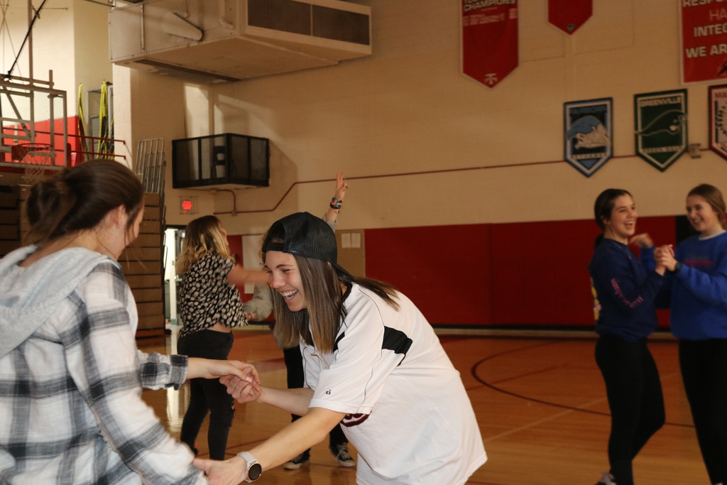 PE teacher Mrs. Matthews laughing as she teaches dance steps to a student.