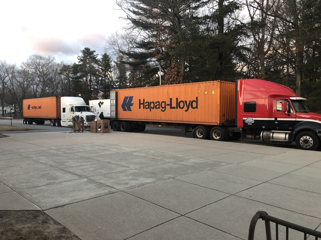 Shipping containers on trucks in front of school