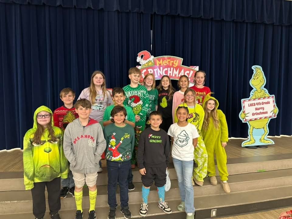 students pose for a holiday photo with Grinch backdrop