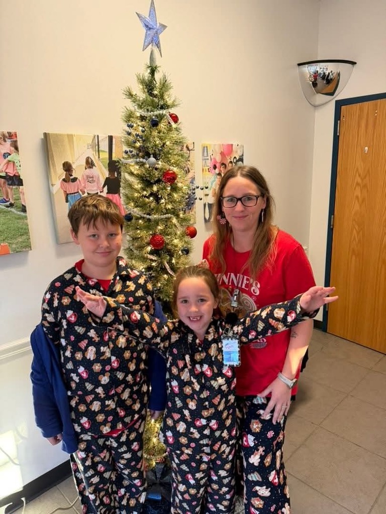family in christmas pajamas in front of the Christmas tree in the school lobby