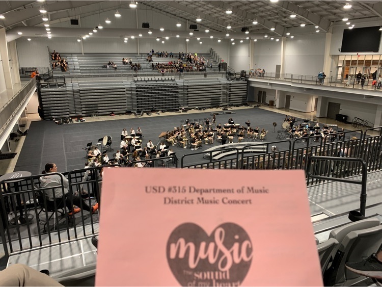 School bands of different ages behind a pink concert program.