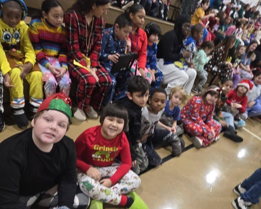 A group of students dressed in festive clothing sitting on the floor and smiling.