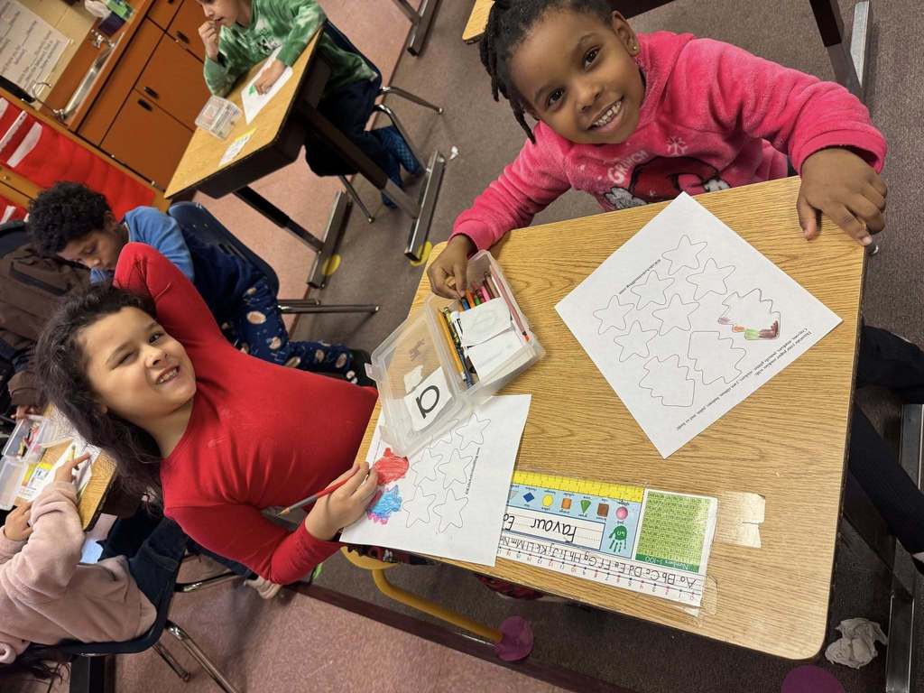 Two young girls coloring and smiling at the camera.