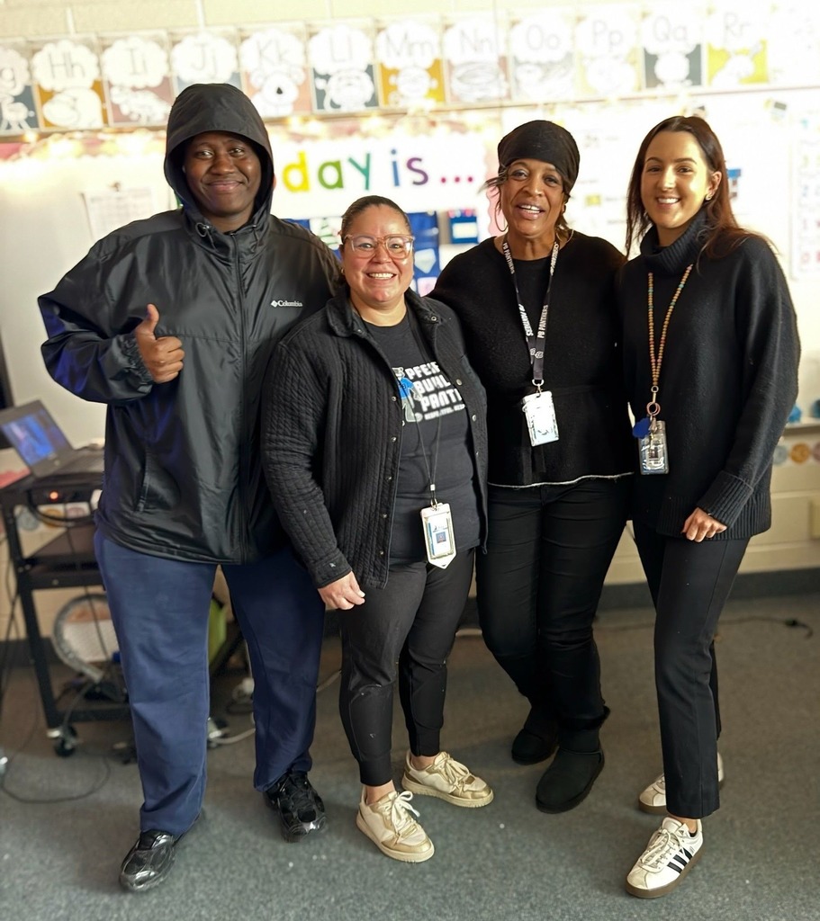 one man and four females standing and smiling, and are all dressed in black.