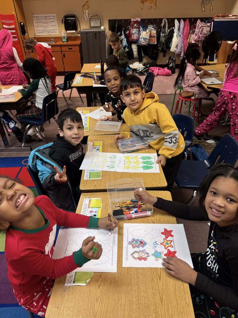 A group of students coloring and smiling at the camera.