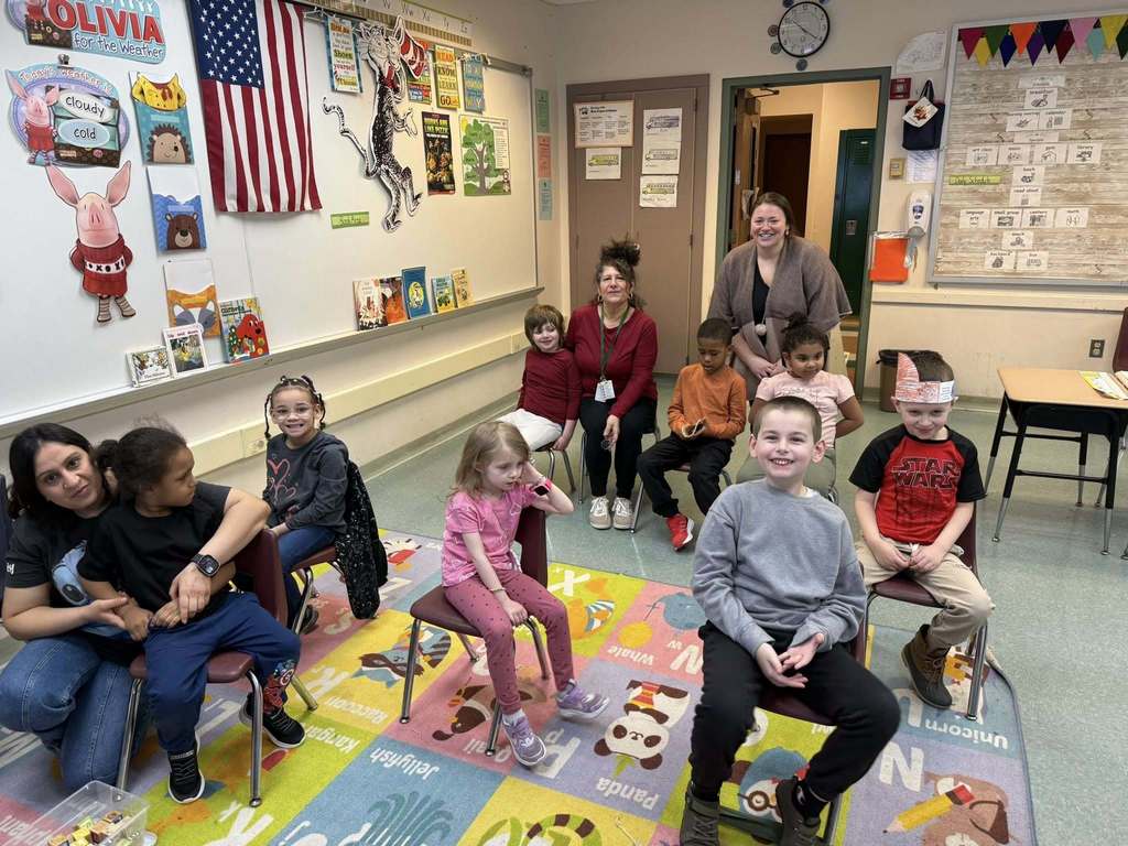 A group of kids smiling in a classroom. 