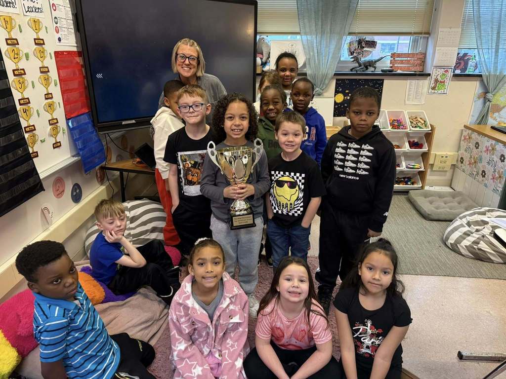 A group of kids smiling in a classroom. 