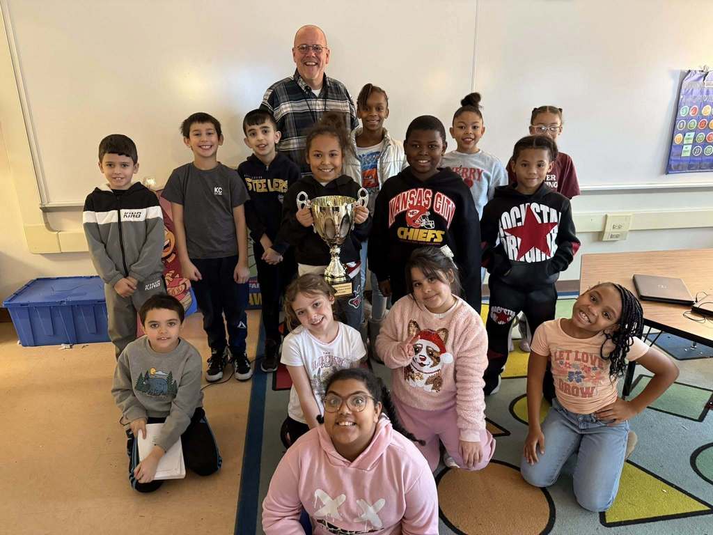 A group of kids smiling in a classroom. 