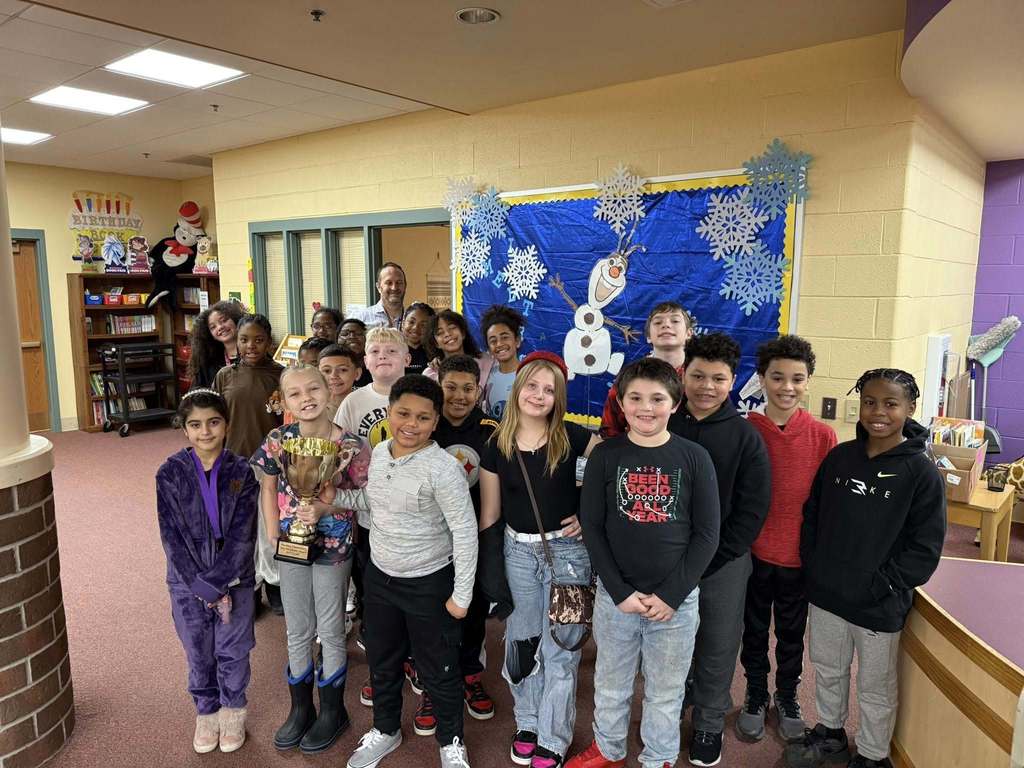 A group of kids smiling in a classroom. 