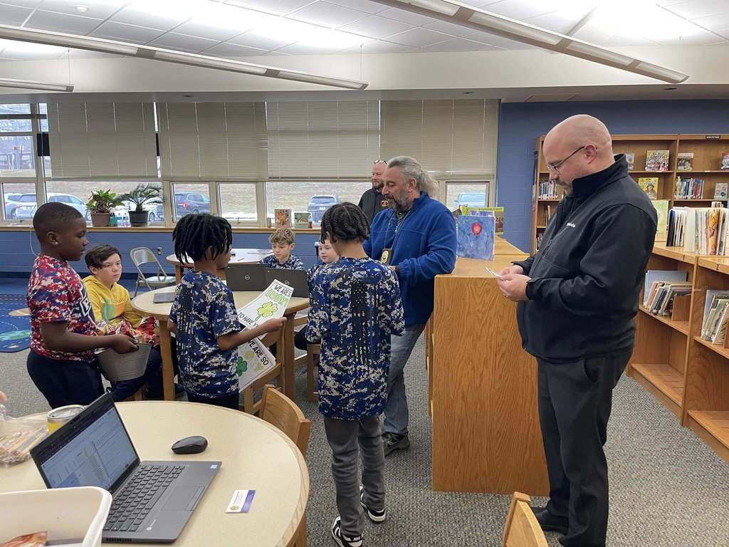 Students and adults standing in a library. 