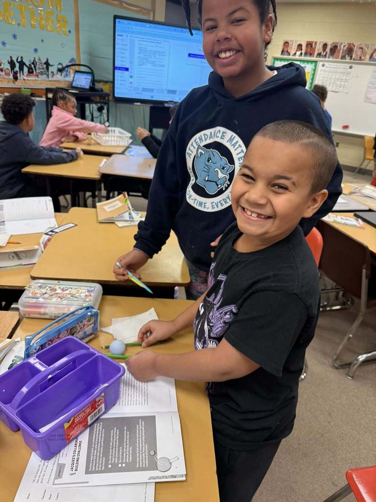 Students in a classroom and smiling.