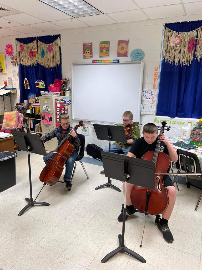 Students playing string instruments in a classroom setting