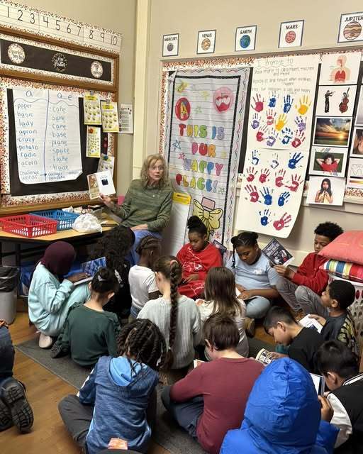 Adult reading to students in a classroom. 