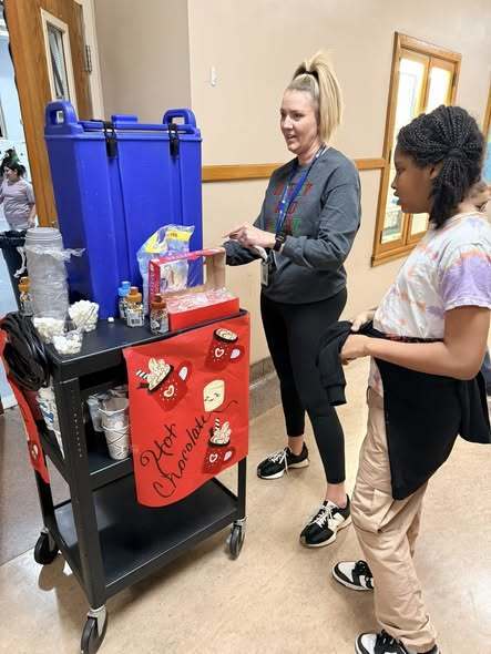 Adult fand child standing by the hot chocolate stand.