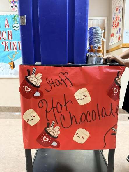 Red sign that says "Staff Hot Chocolate" and has images of hot chocolate and marshmallows on it.