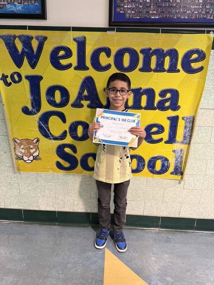 Young boy wearing glasses and holdiing his certificate. 