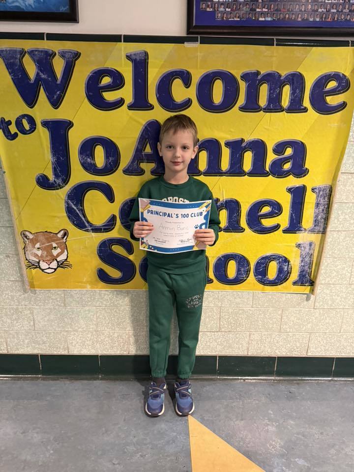 Young boy in all green holding his certificate. 