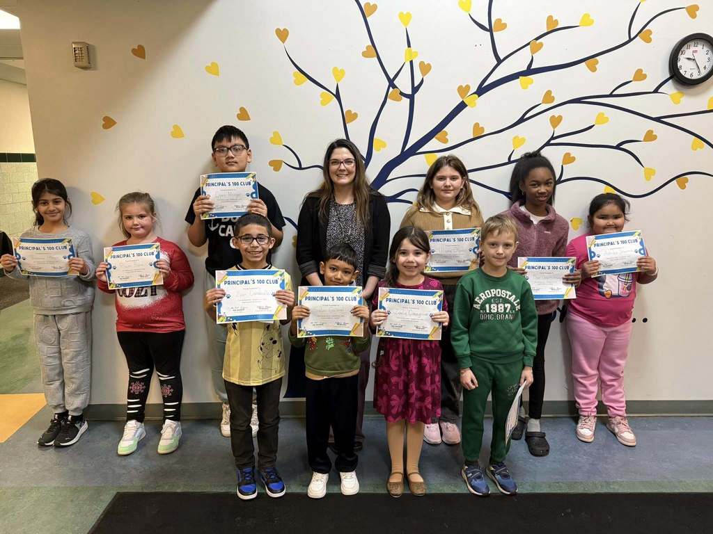 Students and adult standing while students hold certificates up. 