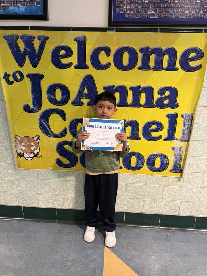 Young boy in a green shirt holding hist certificate. 