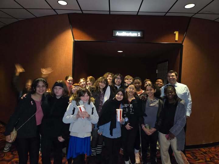 Group od students smiling in the hall of a movie theater. 