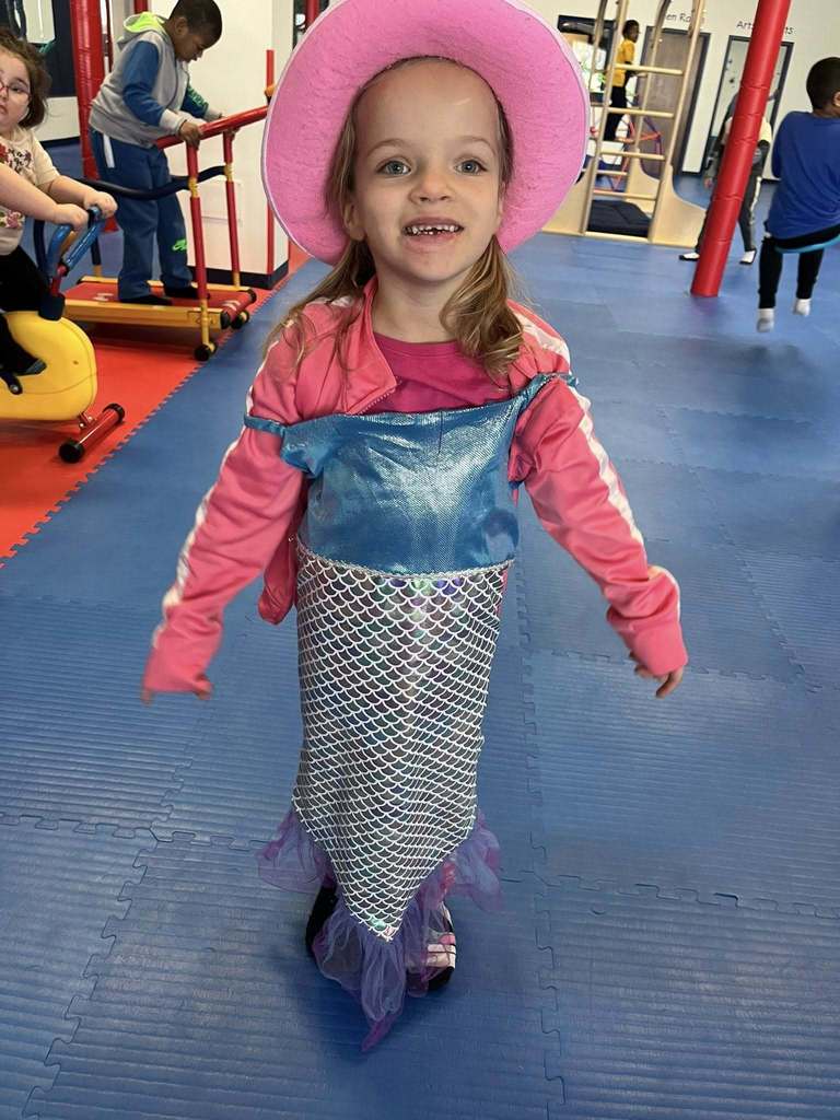 Young girl wearing a pink hat and mermaid outfit.