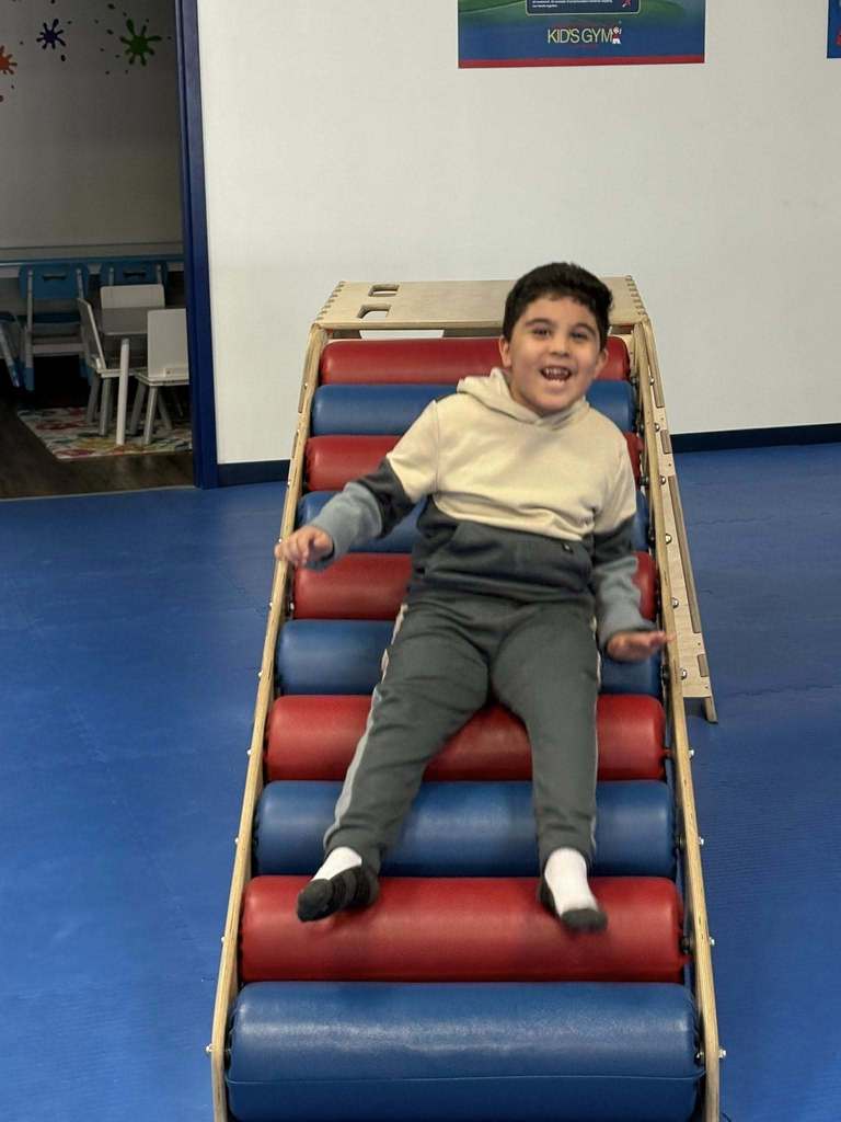 Young boy smiling on a slide.