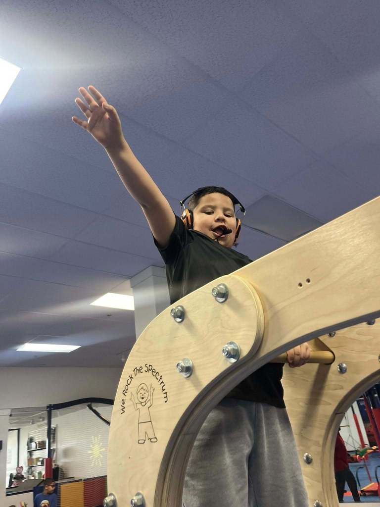 Young boy wearing headphones with arms out.