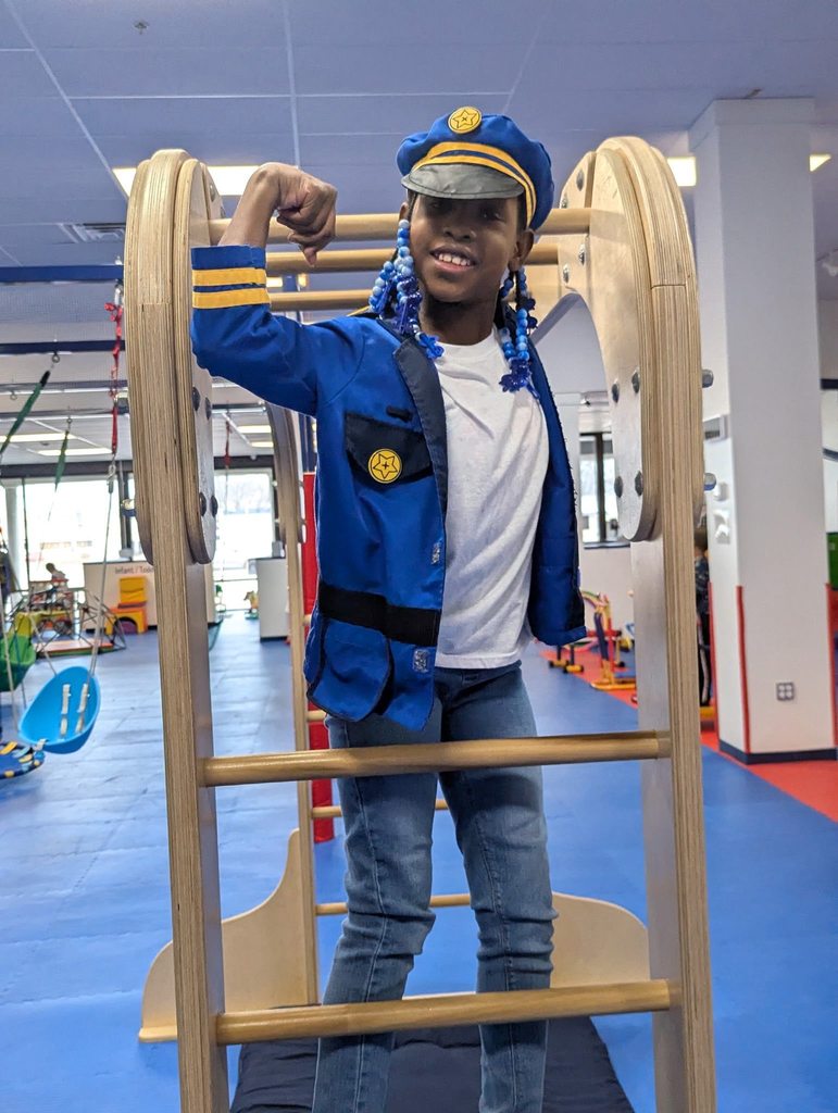 Young boy flexing in a police play uniform.