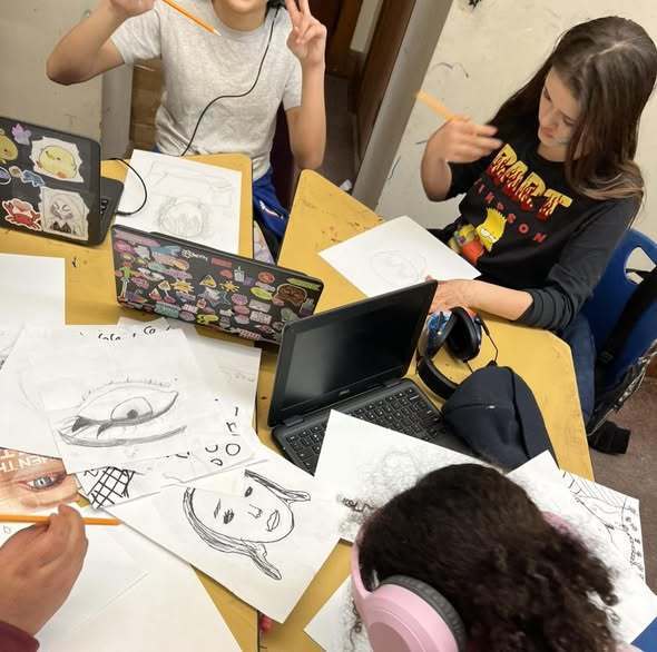 Students drawing on paper at their desks. 
