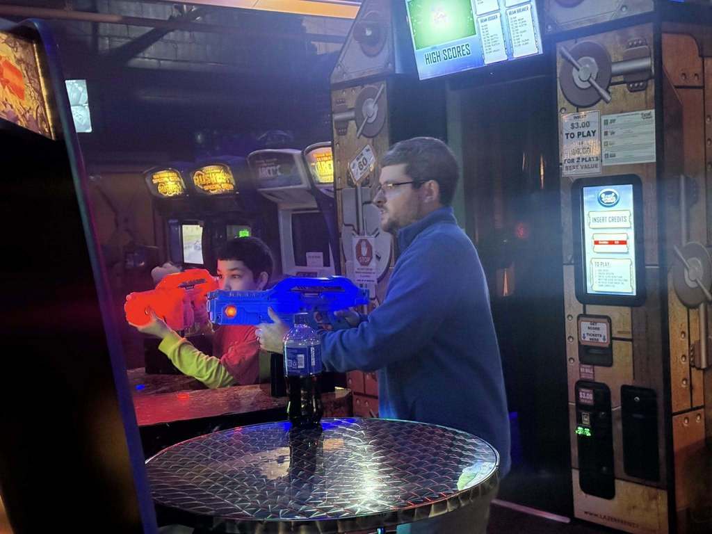 A young boy and adult playing arcade games. 
