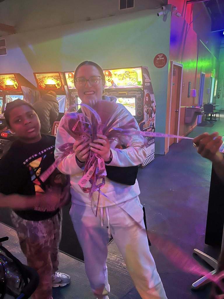 A young girl holding a lot of pink tickets in her hands and smiling. 