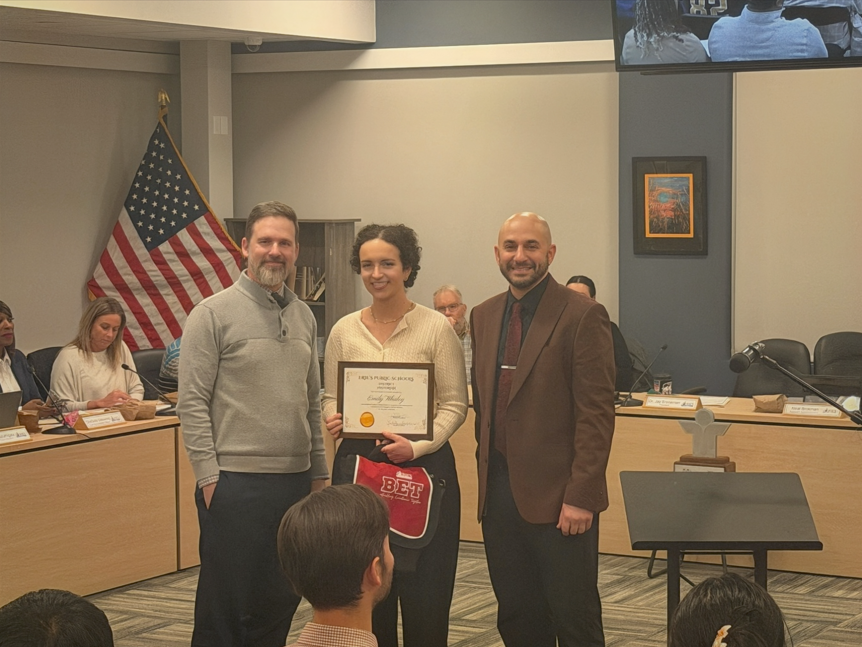 Women standing with two men and holding her certificate.