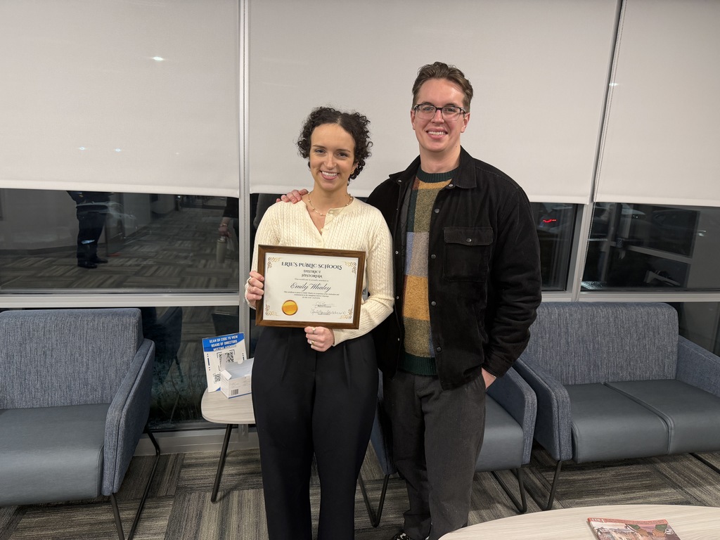 Women standing with a man and holding her certificate.