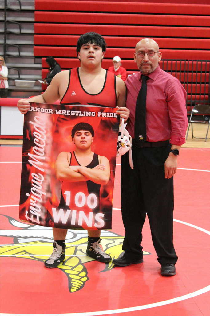 A wrestler hold up a banner while his coach stands next to him.