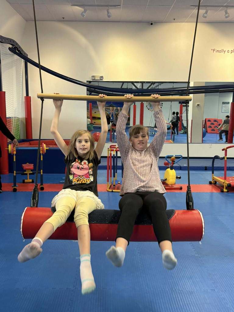 Two young girls swinging in a gym.