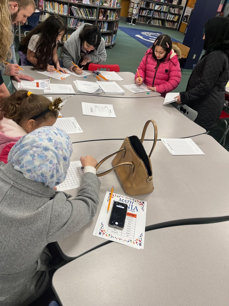 Children and adults gathered around school desks and playing games.