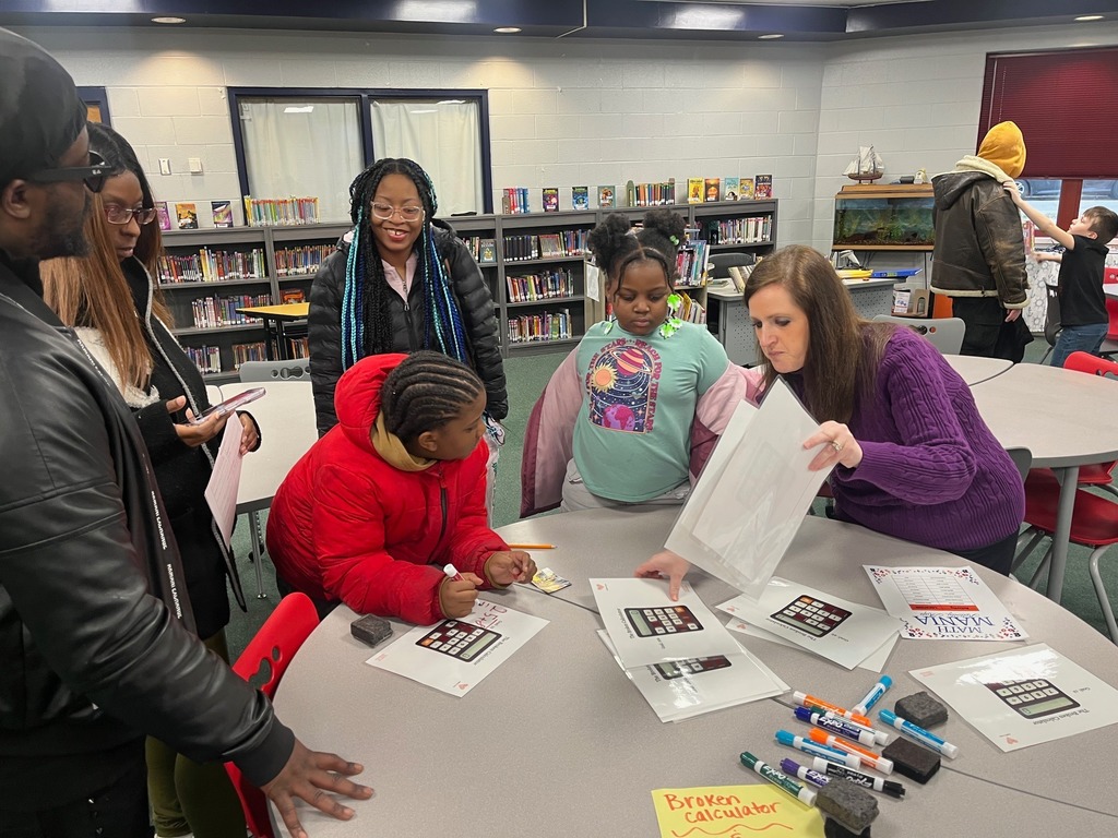 Children and adults gathered around school desks and playing games.