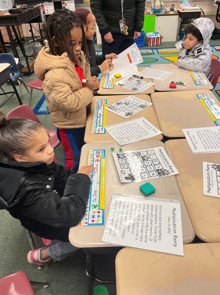 Children at their desks in a classroom with papers on the desk.