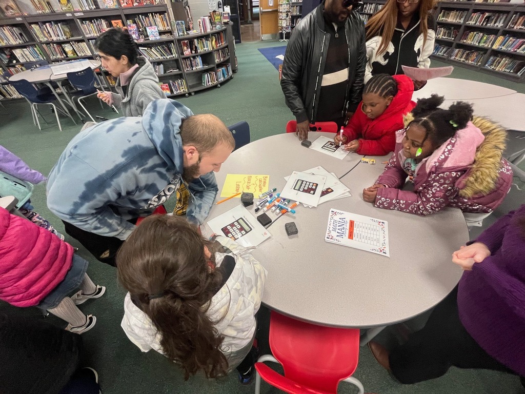 Children and adults gathered around school desks and playing games.