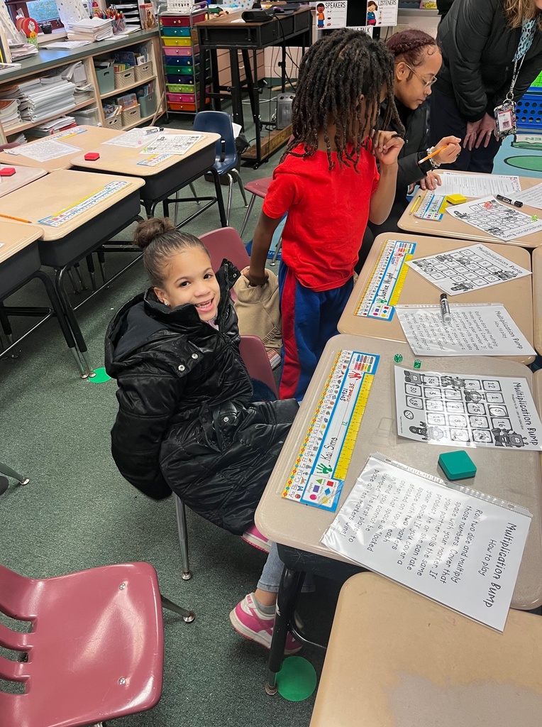 Young girl smiling while sitting in a classroom.