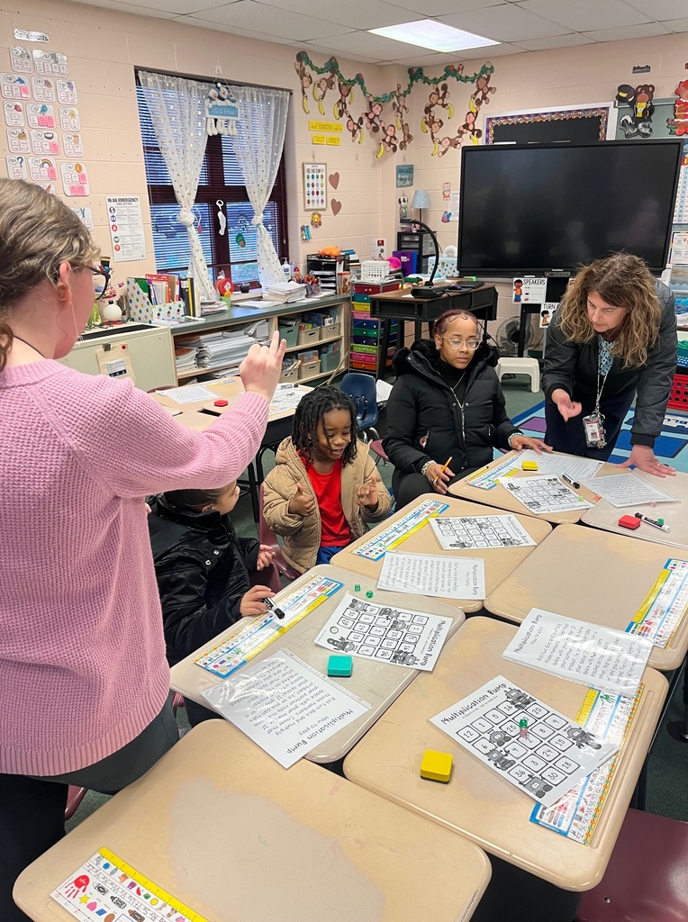 Children and adults gathered around school desks and playing games.