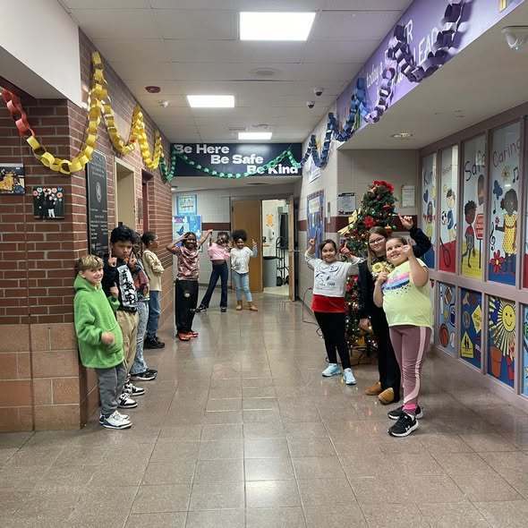 Kids standing in a hall smiling. 