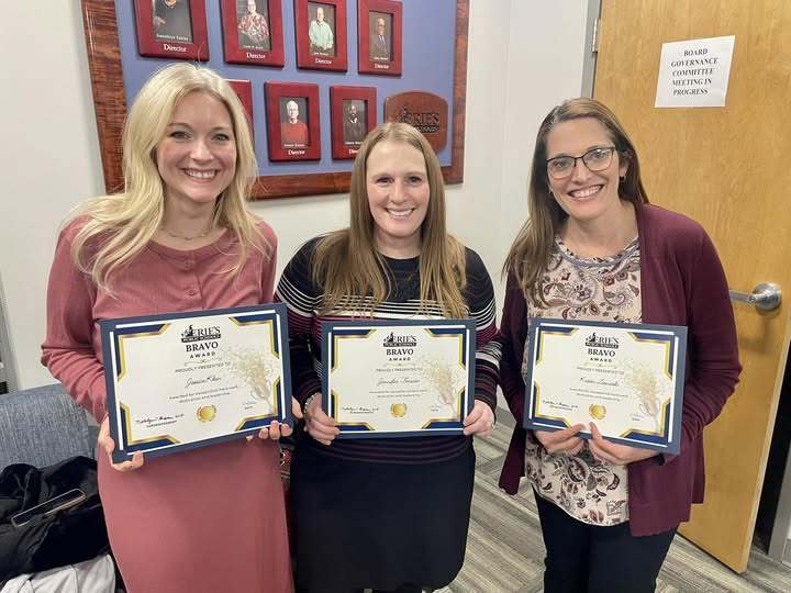 Three women standing and holding their certificates.