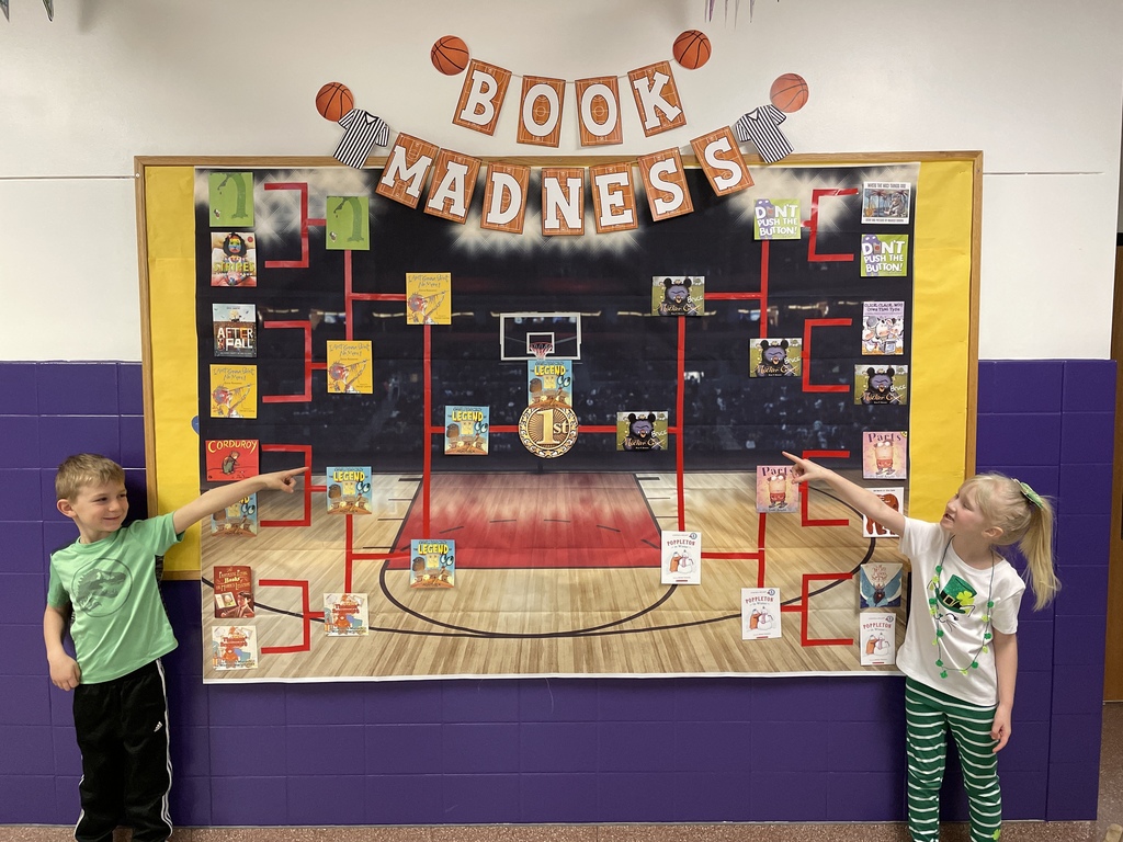 Students point at a bracket of book covers. 