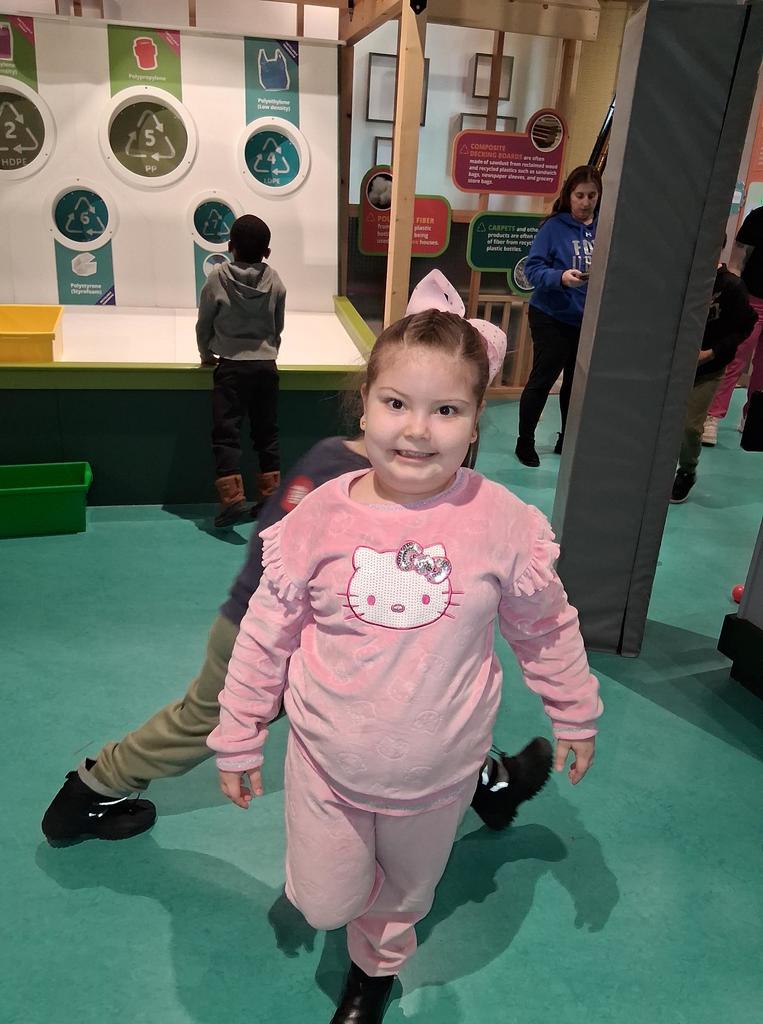 Young girl in a pink outfit smiling. 