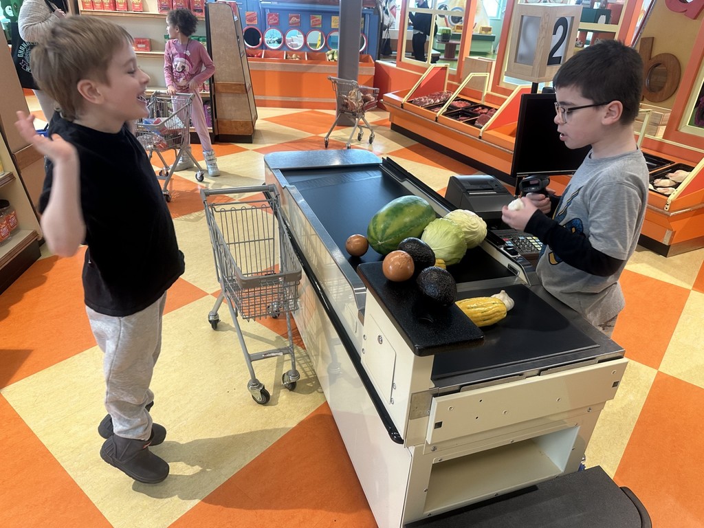 Two young boys at a toy cash register playing. 