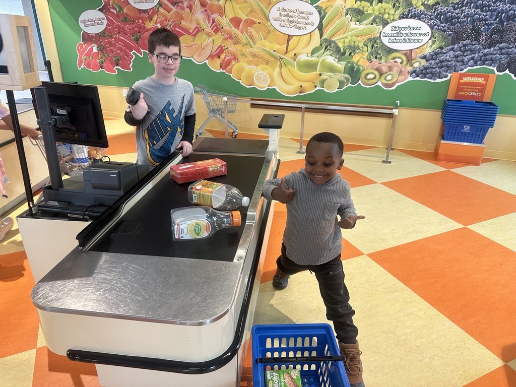 Two young boys at a toy cash register playing. 