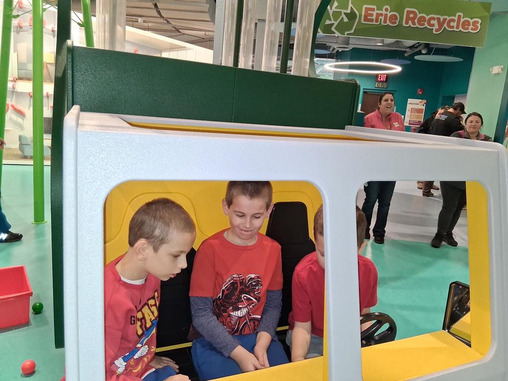 Young boys in a play car sitting next to each other. 