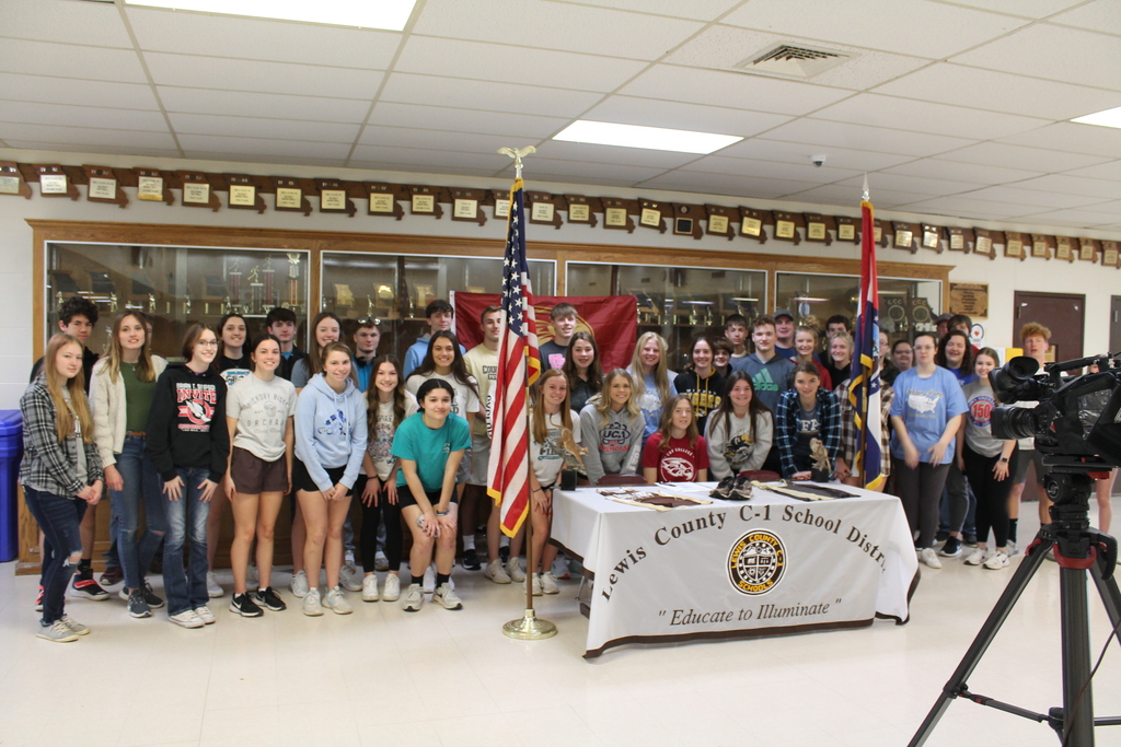 Senior Alexis Vaughn pictured with the Highland Cross Country and Track Teams standing behind her at her college signing.