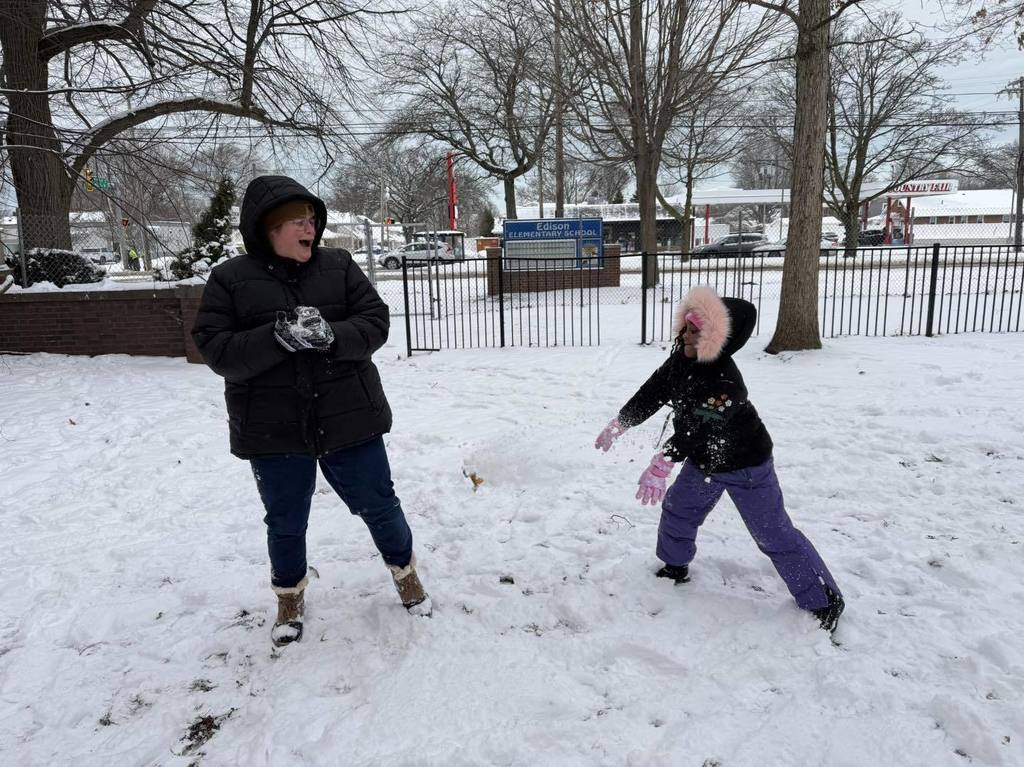 Adult and child playing outside in the snow.